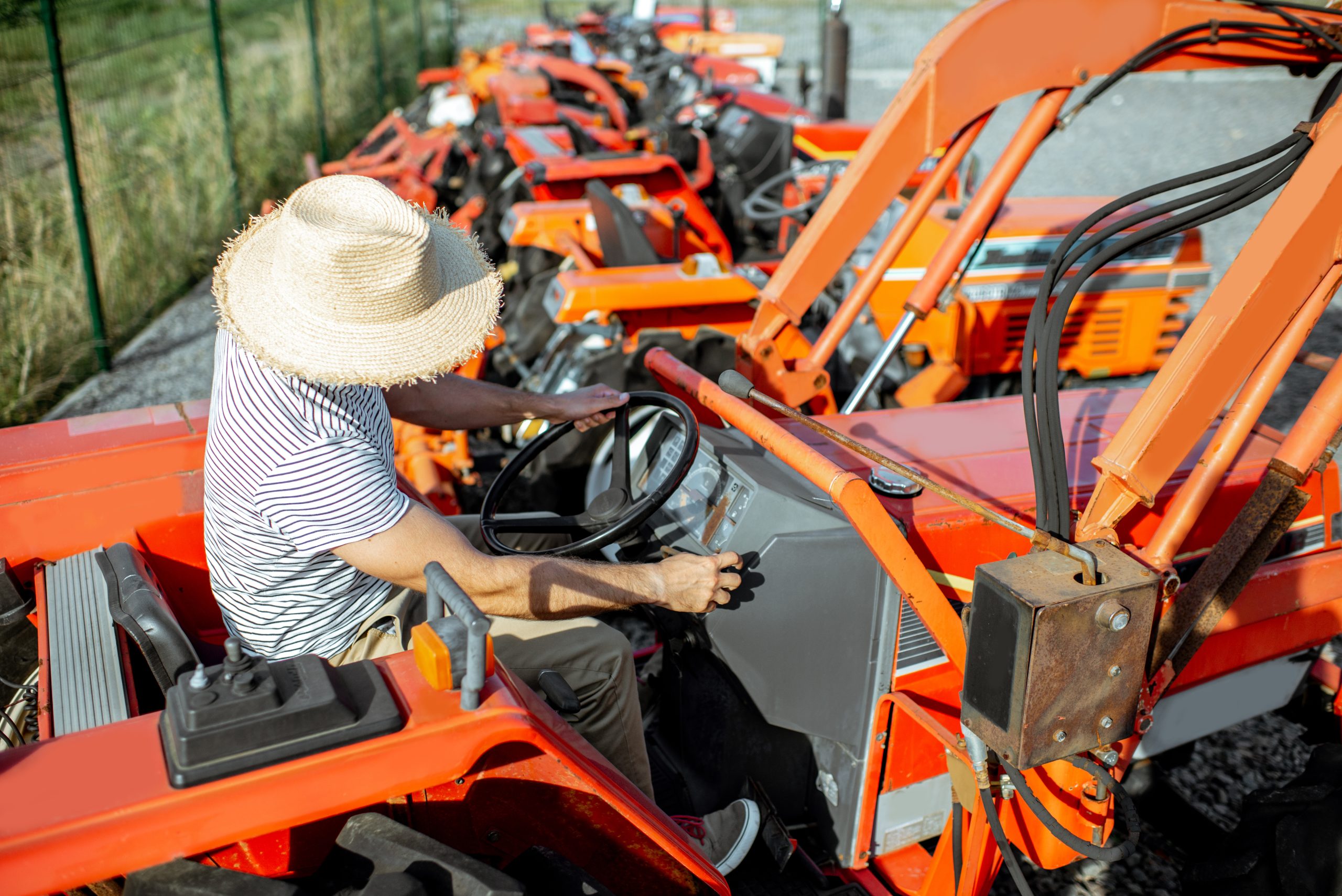Young agronomist trying tractor for farming, choosing agricultural machinery on the open ground of the shop