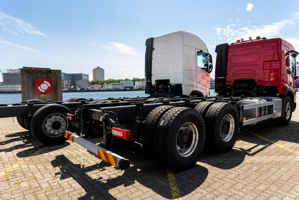 Back view many new heavy commercial cargo transport vehicles stand at port for export import shipping in Germany. Modern semi-trailer business industry truck tractor chassis sale sea logistics.