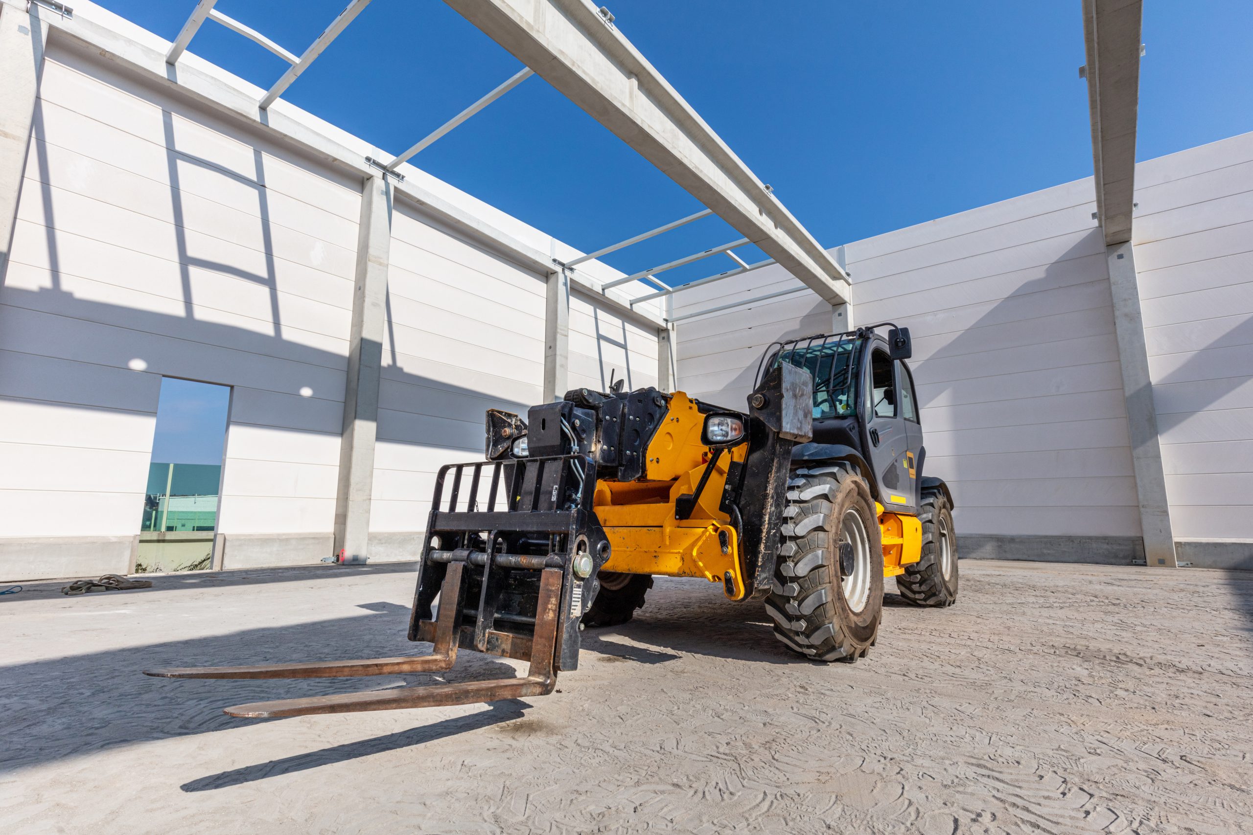 Industrial warehouse construction. Rotating telehandler vehicle. Building a new hall or storehouse.